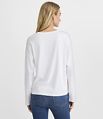 A woman wearing a white long-sleeved shirt and blue jeans stands with her back to the camera against a plain white background. carousel Product Image 4