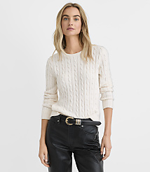 A blonde woman wearing a white cable-knit sweater and black leather pants stands against a plain white background. carousel Product Image 1