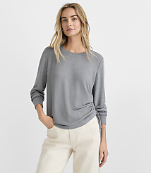 A blonde woman wearing a grey long-sleeved top and white pants stands against a plain white background. carousel Product Image 2