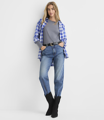 A woman wearing a blue plaid shirt, grey t-shirt, jeans, and black boots stands against a plain white background. carousel Product Image 2
