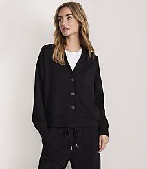 A woman wearing a black button-up jacket and matching pants stands against a plain, light-colored background. carousel Product Image 2