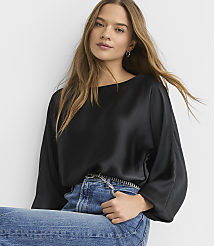 A woman wearing a black satin blouse and blue jeans poses against a plain white background. carousel Product Image 1
