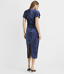 A woman stands with her back to the camera wearing a navy blue velvet midi dress against a plain white background. carousel Product Image 3