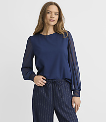 A woman wearing a navy blue blouse and pinstriped trousers stands against a plain white background. carousel Product Image 2