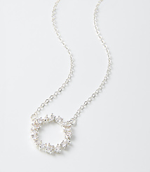 A silver necklace with a circular diamond-encrusted pendant rests on a plain white background. carousel Product Image 2