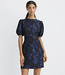A woman wearing a short, blue floral jacquard dress with puff sleeves stands against a plain white background. carousel Product Image 2