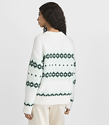 A woman wearing a white and green patterned sweater and white pants stands against a plain light gray background. carousel Product Image 3