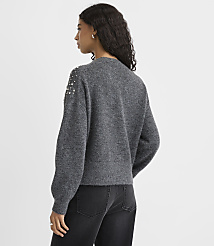 A woman wearing a grey studded sweater and black jeans stands against a plain white background. carousel Product Image 3