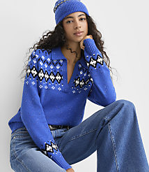 A woman wearing a blue patterned sweater, blue beanie, and jeans poses against a plain white background. carousel Product Image 2