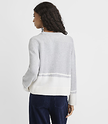 A woman wearing a grey and white striped sweater and navy blue pants stands against a plain light grey background. carousel Product Image 4