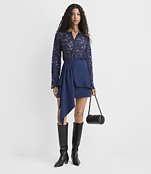 A woman wearing a navy blue lace top, a matching draped skirt, and tall black boots stands against a plain white background. carousel Product Image 1
