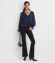 A woman wearing a blue floral blouse and black flared trousers stands against a plain white background. carousel Product Image 2