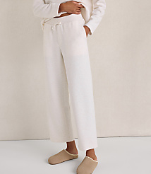 A person wearing cream-colored lounge pants and beige slippers stands against a plain, neutral-toned wall. carousel Product Image 2