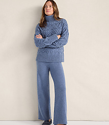 A woman wearing a blue cable-knit sweater and matching wide-leg trousers stands against a plain, light-colored background. carousel Product Image 1