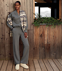 A woman wearing a grey lounge set and a patterned scarf stands on a wooden deck against a rustic wooden wall with a window and greenery. carousel Product Image 4