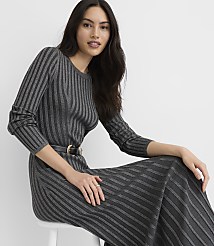 A woman wearing a grey ribbed dress and a black belt sits on a white stool against a plain white background. carousel Product Image 1