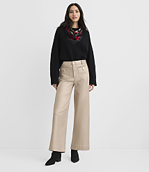 A woman wearing a black sweater, a patterned scarf, and wide-leg beige trousers stands against a plain white background. carousel Product Image 1