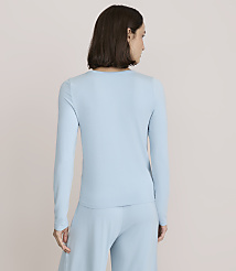 A woman wearing a light blue long-sleeved top and matching pants stands with her back to the camera against a plain, neutral background. carousel Product Image 3