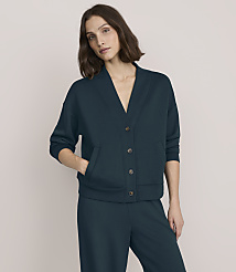 A woman wearing a dark teal button-up cardigan and matching trousers stands against a plain, light beige background. carousel Product Image 1