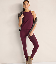 A woman wearing a maroon tank top and leggings with a patterned cardigan draped over her shoulders stands against a plain, light-colored wall. carousel Product Image 1