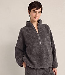 A woman with short brown hair wears a charcoal grey fleece quarter-zip pullover and matching pants against a plain, light-colored background. carousel Product Image 1