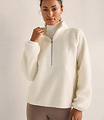 A woman wearing a white fleece pullover and a white turtleneck stands against a plain, neutral-toned background. carousel Product Image 1