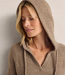 A blonde woman wearing a brown hooded sweater stands against a plain, light-colored wall. carousel Product Image 4