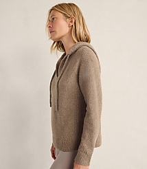 A blonde woman wearing a taupe hooded sweater stands in profile against a plain, light-colored wall. carousel Product Image 3