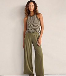 A woman wearing a striped tank top and olive green wide-leg pants stands against a plain, neutral-colored wall. carousel Product Image 1