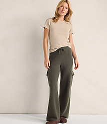 A woman wearing a beige t-shirt and olive green wide-leg pants stands against a plain, light-colored wall. carousel Product Image 2