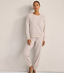 A woman wearing a beige polka-dot pajama set stands against a plain, light-colored wall. carousel Product Image 2