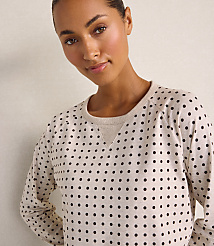 A woman wearing a beige polka-dot shirt stands against a plain, light-colored wall. carousel Product Image 3