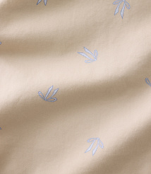 Small, light blue floral patterns are scattered across a draped, beige fabric background. carousel Product Image 4