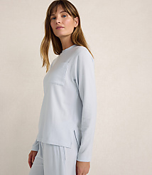 A woman wearing light blue loungewear stands against a plain, neutral-toned background. carousel Product Image 3