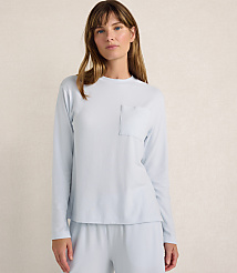 A woman wearing a light blue long-sleeved shirt and matching pants stands against a plain, neutral-toned wall. carousel Product Image 1