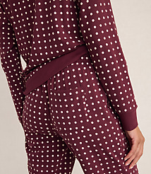 A person wears maroon pajamas with white polka dots against a plain, light-colored background. carousel Product Image 3
