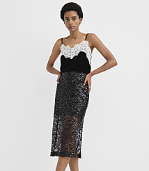 A woman wearing a denim jacket and a shimmering black sequined skirt stands against a plain white background. carousel Product Image 1