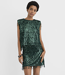 A woman wearing a shimmering green sequined dress, long black gloves, and black flats stands against a plain white background. carousel Product Image 1