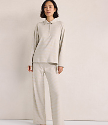 A woman wearing a light-colored, long-sleeved collared shirt and matching wide-leg pants stands against a plain, neutral-toned background. carousel Product Image 2