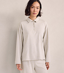 A woman wearing a light-colored striped polo shirt and matching pants stands against a plain, neutral-toned wall. carousel Product Image 1