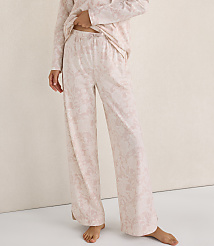 A person wears light pink floral pajamas while standing against a plain, neutral-toned wall. carousel Product Image 2