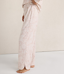 A person wearing light pink floral pajama pants stands against a plain, neutral-toned wall and floor. carousel Product Image 3