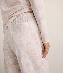 A person wears light pink floral print pajamas against a plain, neutral-toned background. carousel Product Image 4