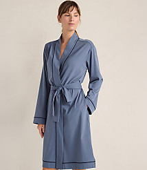 A woman wearing a blue robe with a tie waist stands against a plain, neutral-colored wall. carousel Product Image 1