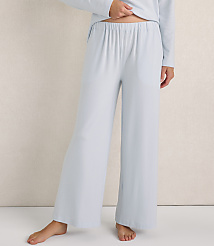 A person wears light blue wide-leg lounge pants against a plain, neutral-toned wall. carousel Product Image 2