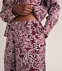A person wears a maroon and white paisley print pajama set against a plain, light-colored background. carousel Product Image 3
