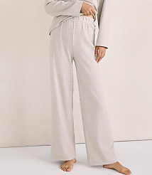 A person wears light-colored, striped lounge pants and a matching top against a plain, neutral-toned wall. carousel Product Image 2