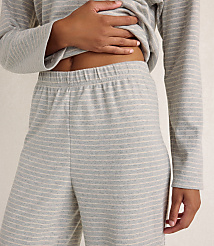 A person wears a grey and white striped lounge set against a plain, neutral-colored wall. carousel Product Image 3