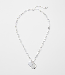 A silver chain necklace with two circular pendants rests on a plain white background. carousel Product Image 1