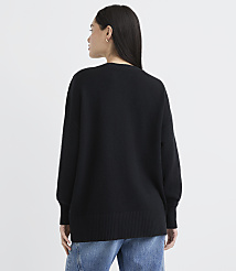 A woman wearing a black oversized sweater and blue jeans stands with her back to the camera against a plain white background. carousel Product Image 3